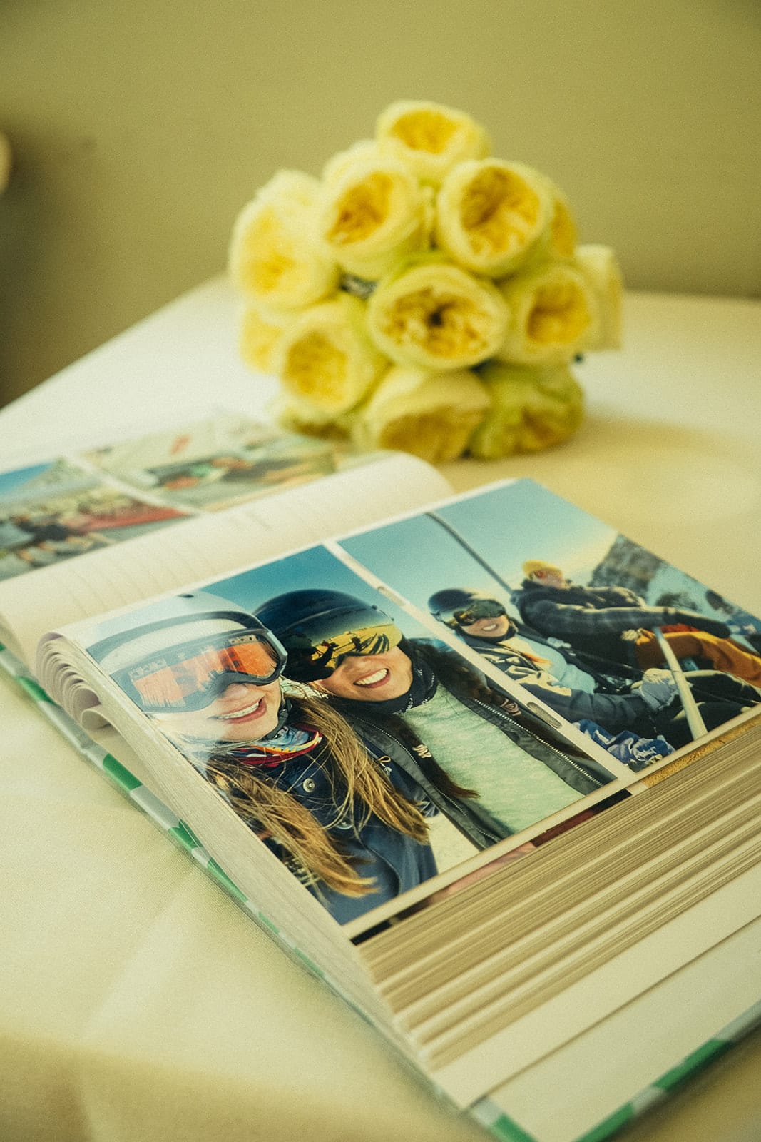 Cecile’s yellow roses resting beside a photo album on a white tablecloth