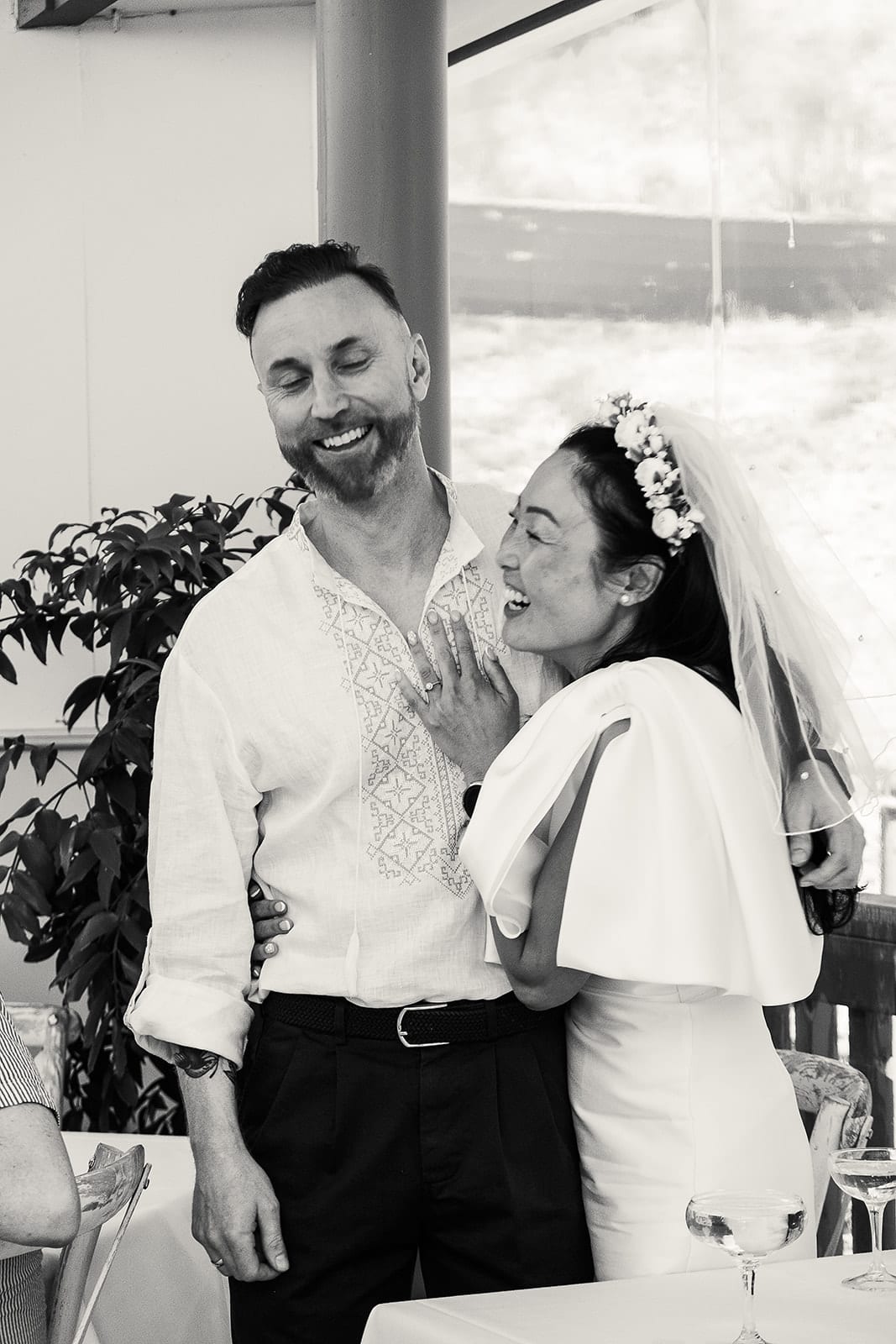 Black and white photo of Cecile and Stefan laughing together during the speeches