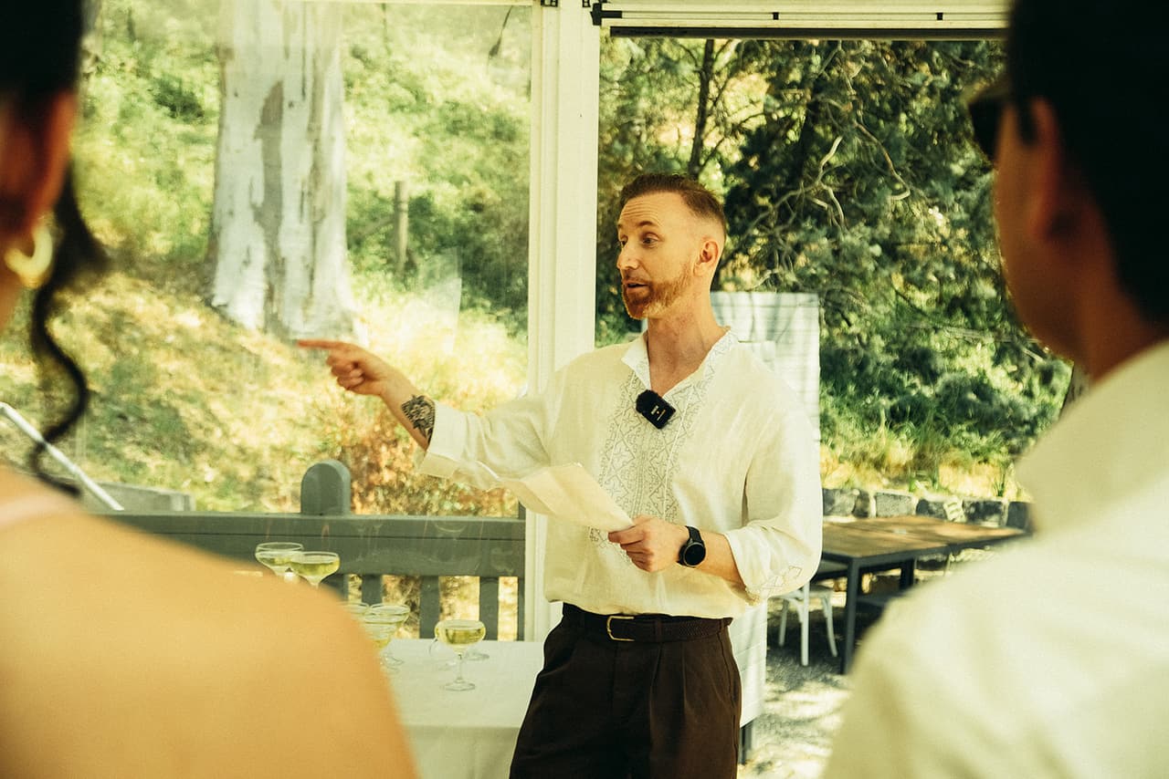Stefan pointing into the room as he gives his speech on the verandah
