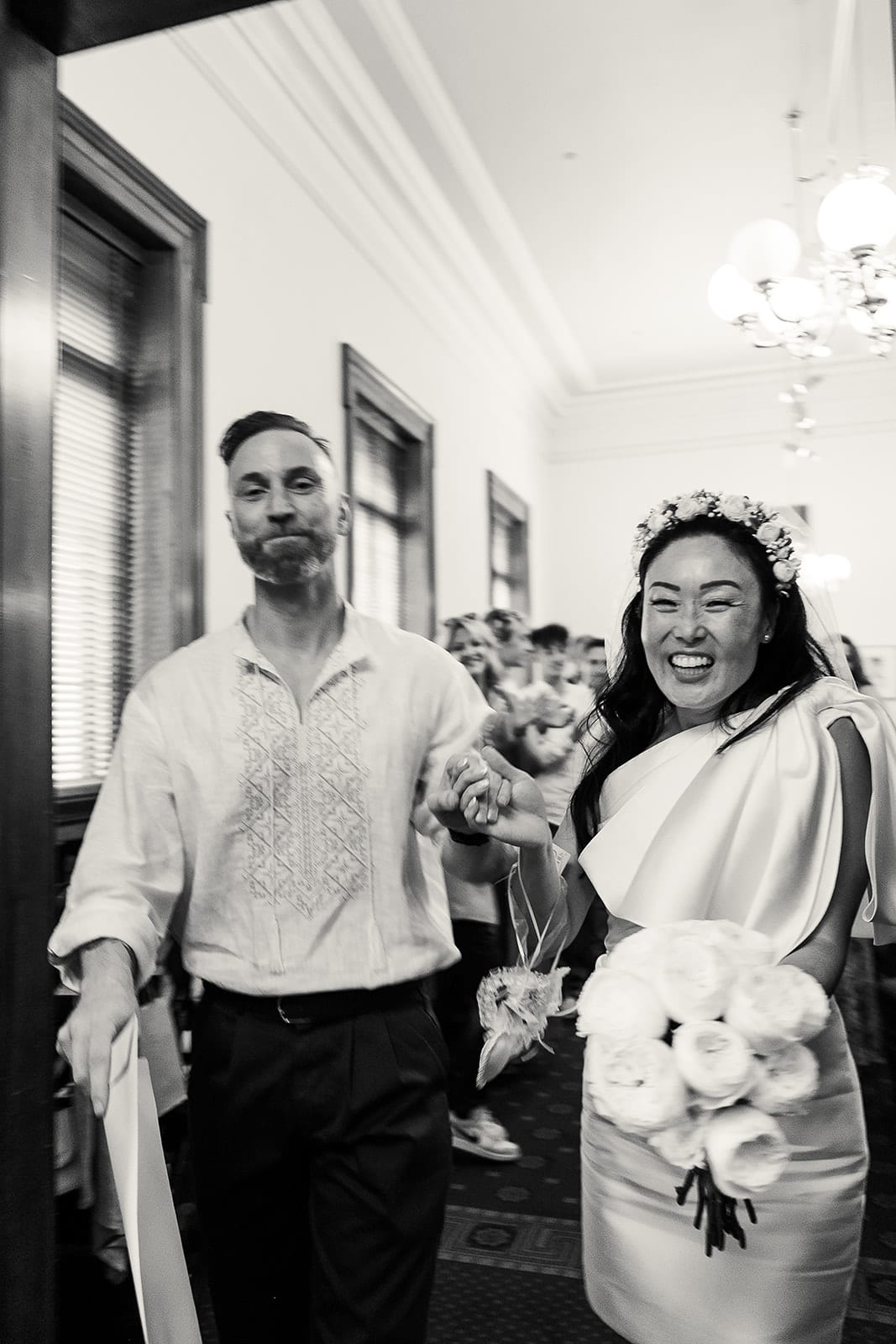 Black and white photo of Cecile and Stefan walking out of the ceremony room as husband and wife
