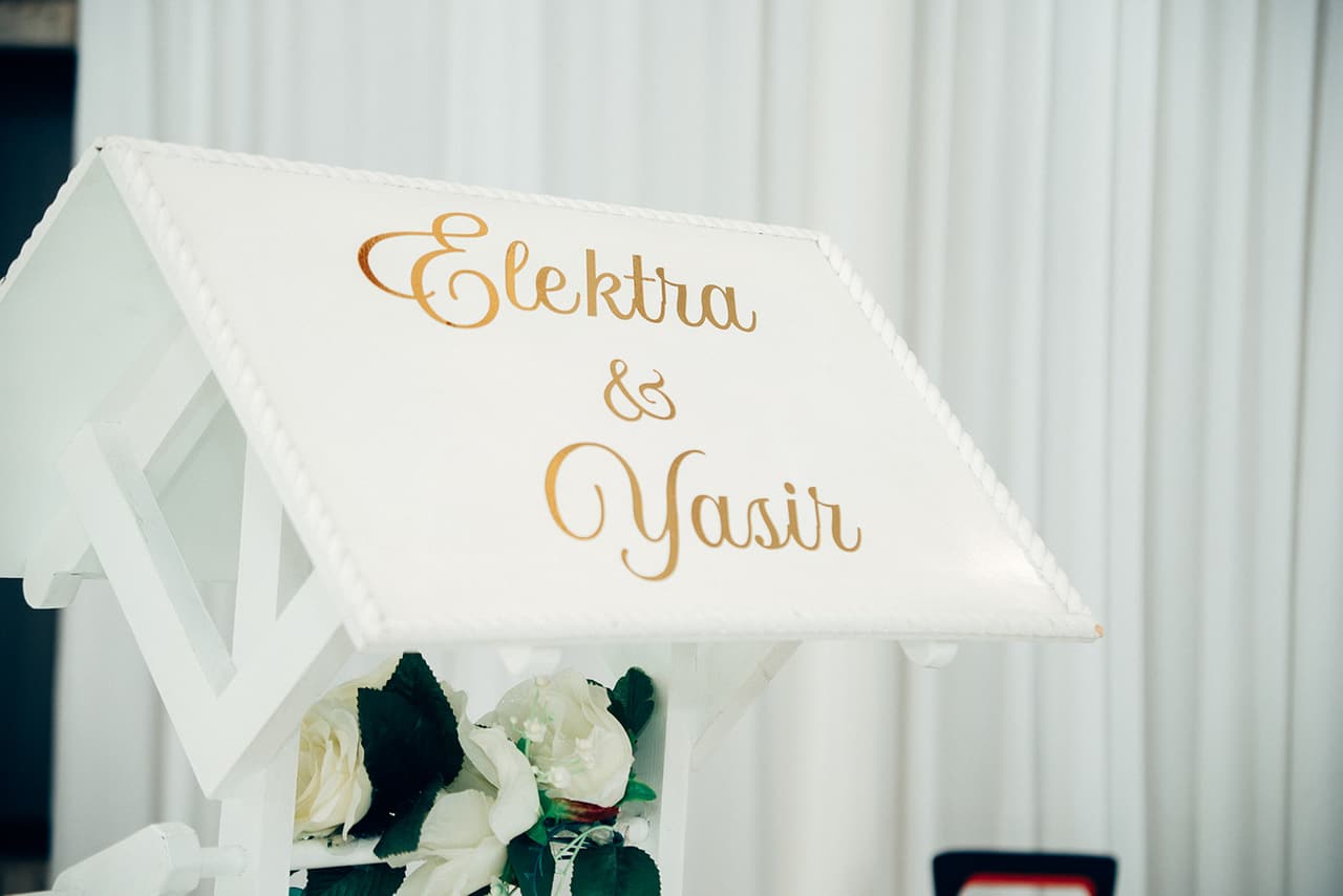 A white sign with Elektra and Yasir’s names in gold script at the reception