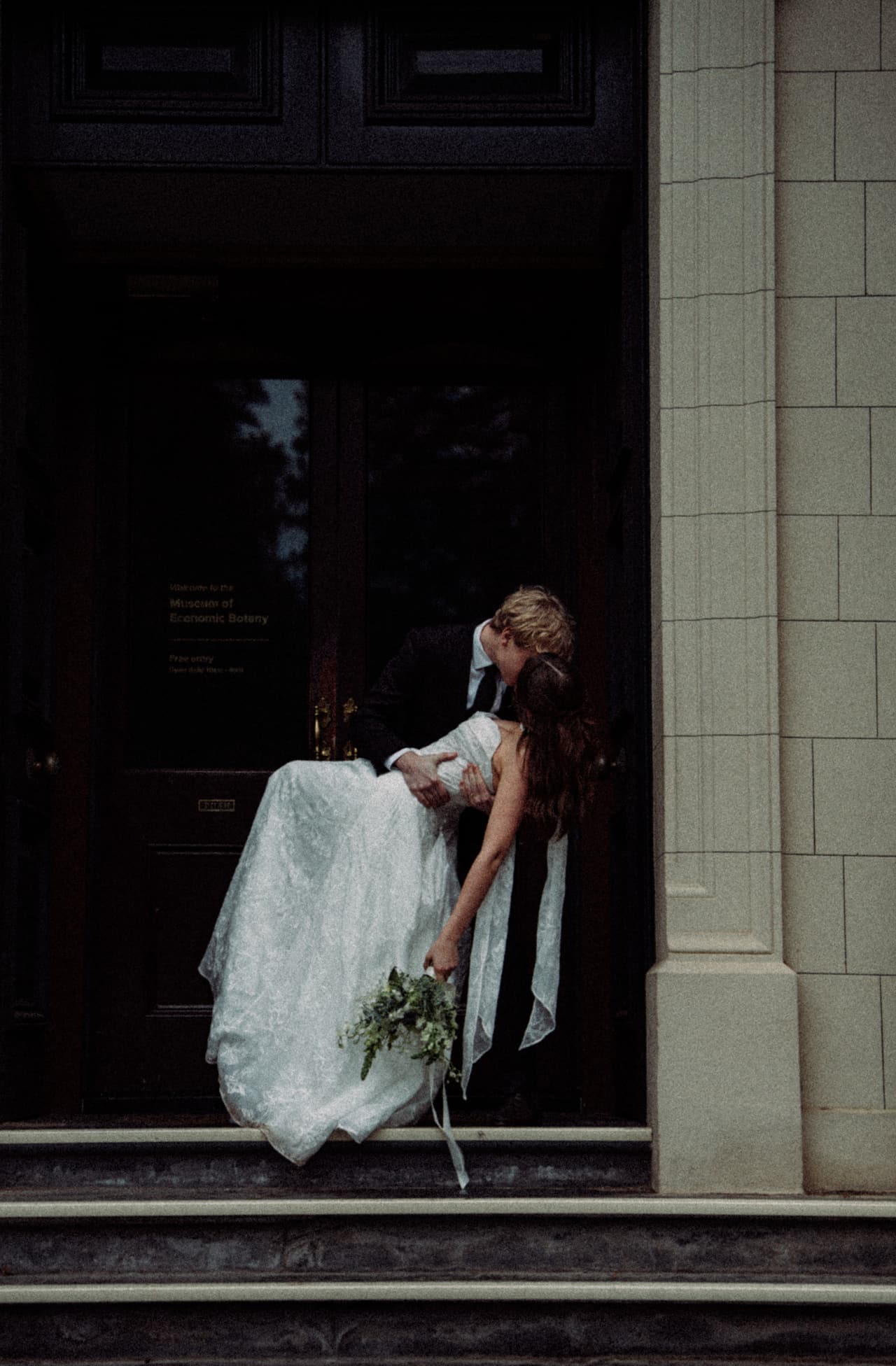 Eli dipping Charlotte for a kiss in the dark doorway of the Museum of Economic Botany