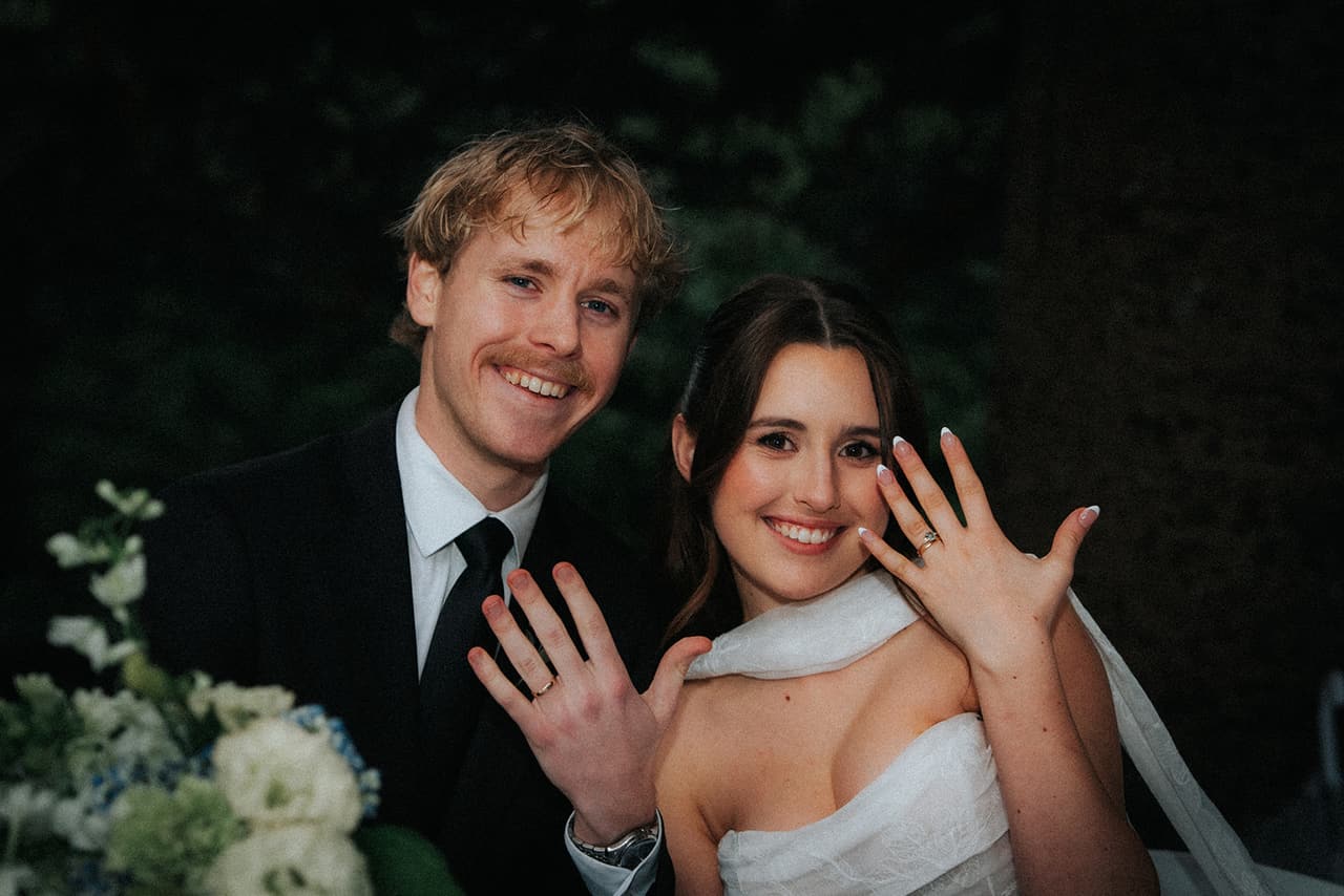 Eli and Charlotte laughing as they hold up their hands to show their wedding rings