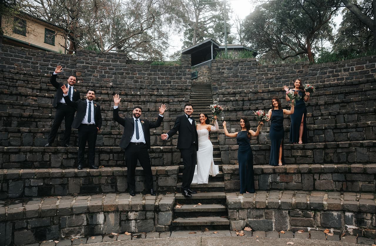 The bridal party waving and cheering on the amphitheatre steps with George and Tia in the middle