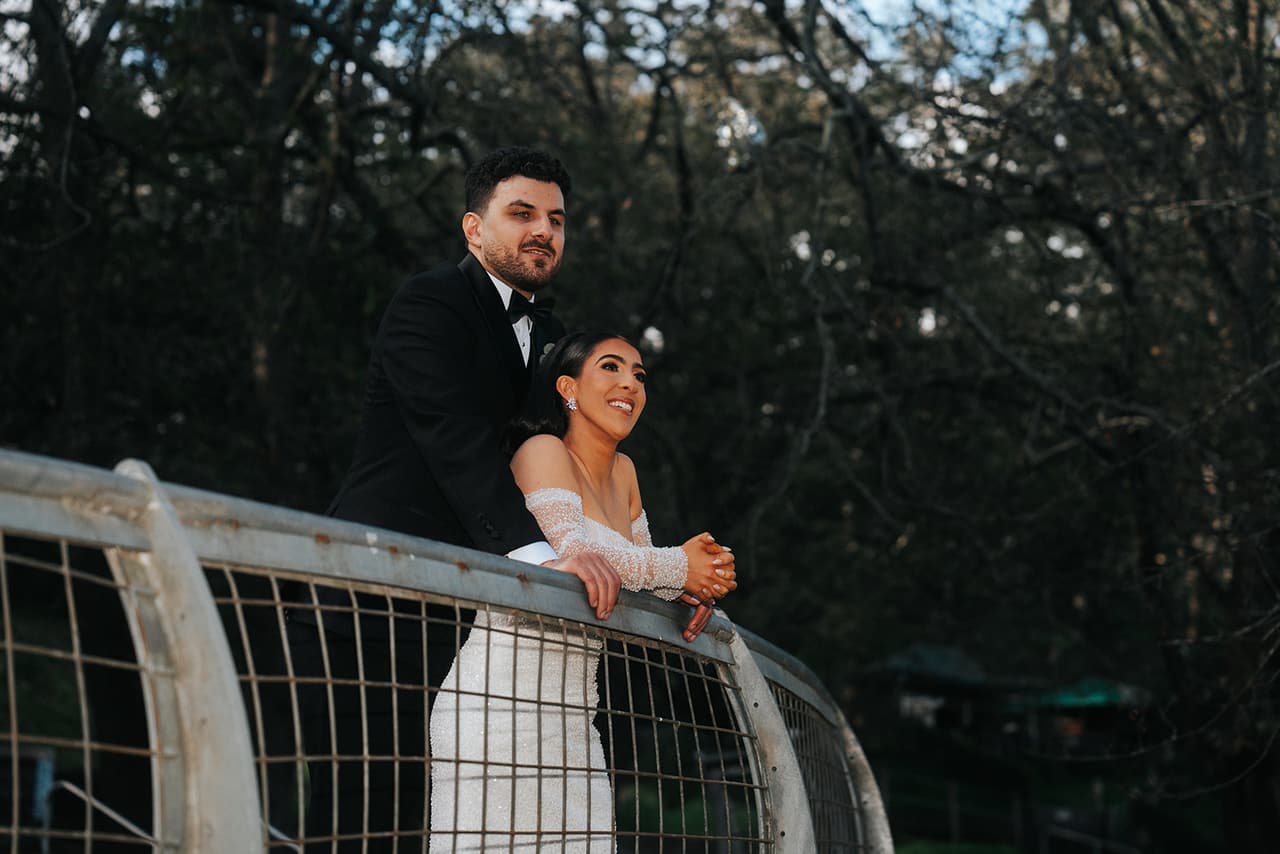 George and Tia leaning on a white railing under bare trees, Tia smiling into the distance