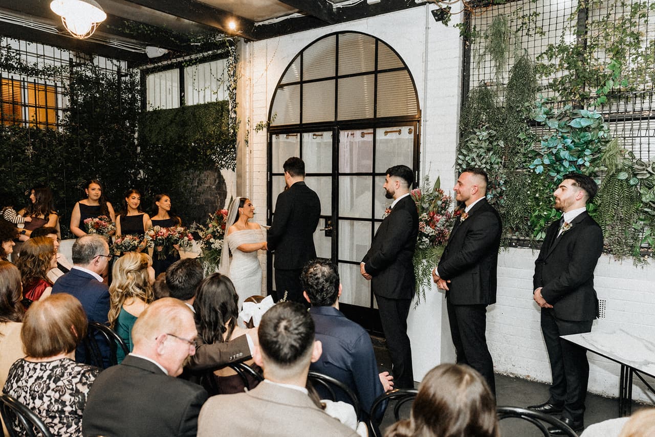 The ceremony at Little Henri from the back, guests seated among the greenery and white walls