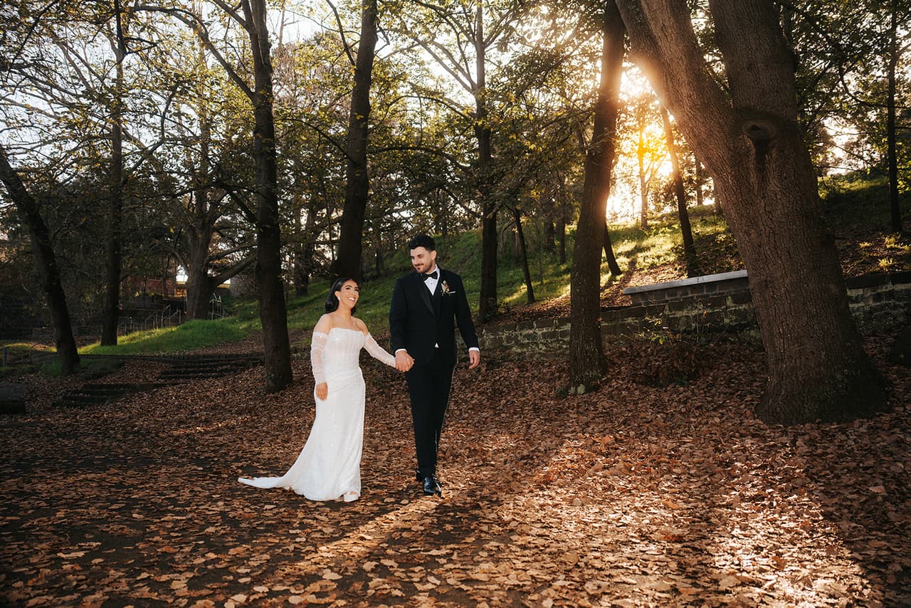 George and Tia walking through fallen leaves with the sun low behind the trees
