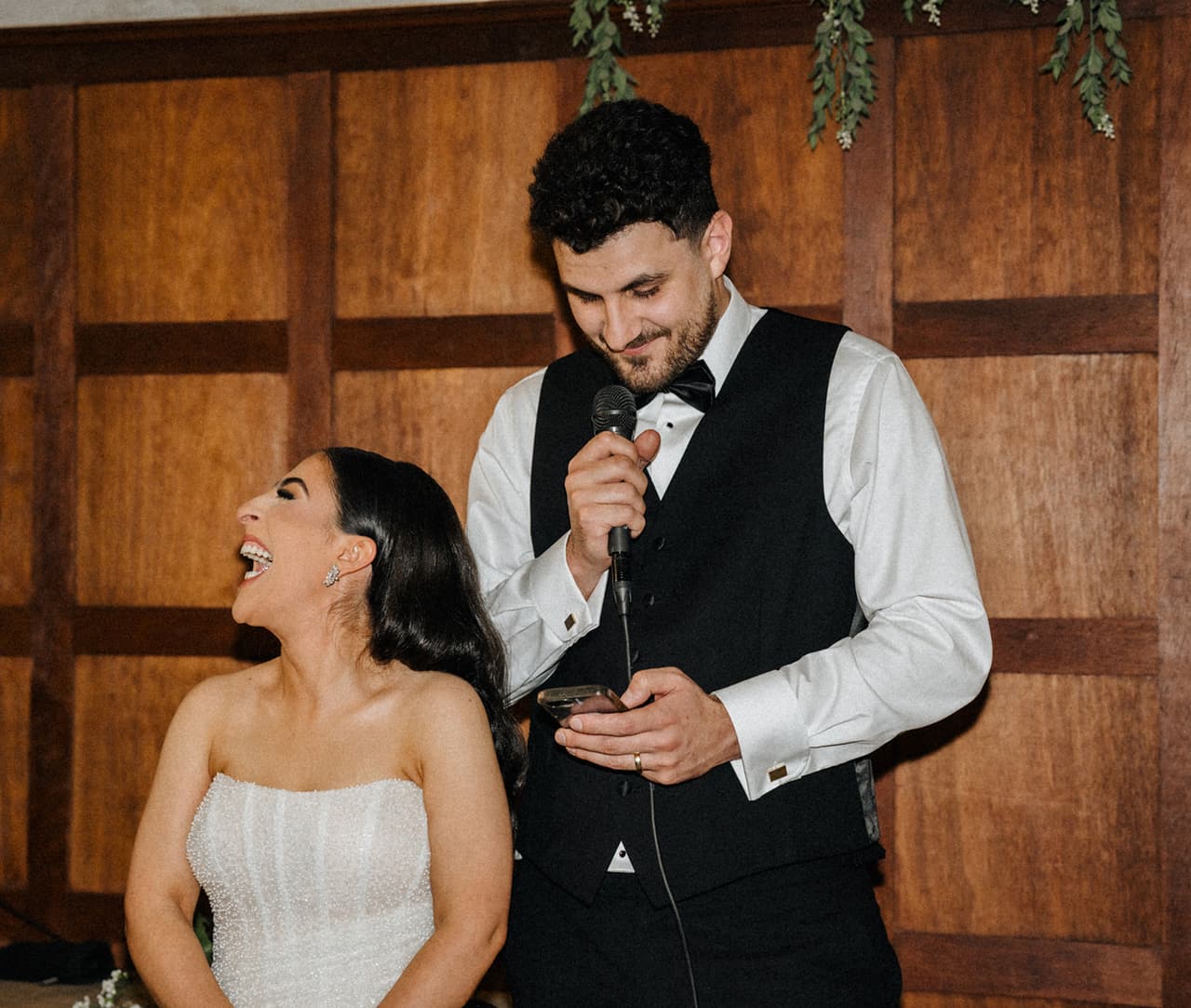 George giving his speech from his phone as Tia laughs beside him