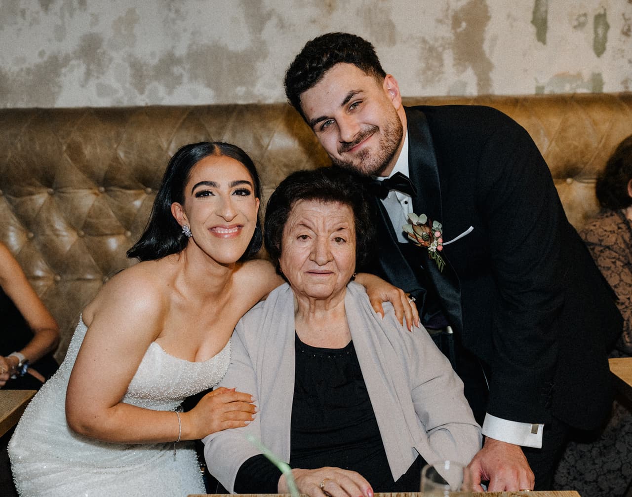 Tia, now in a strapless gown, and George with an older woman on the leather banquette