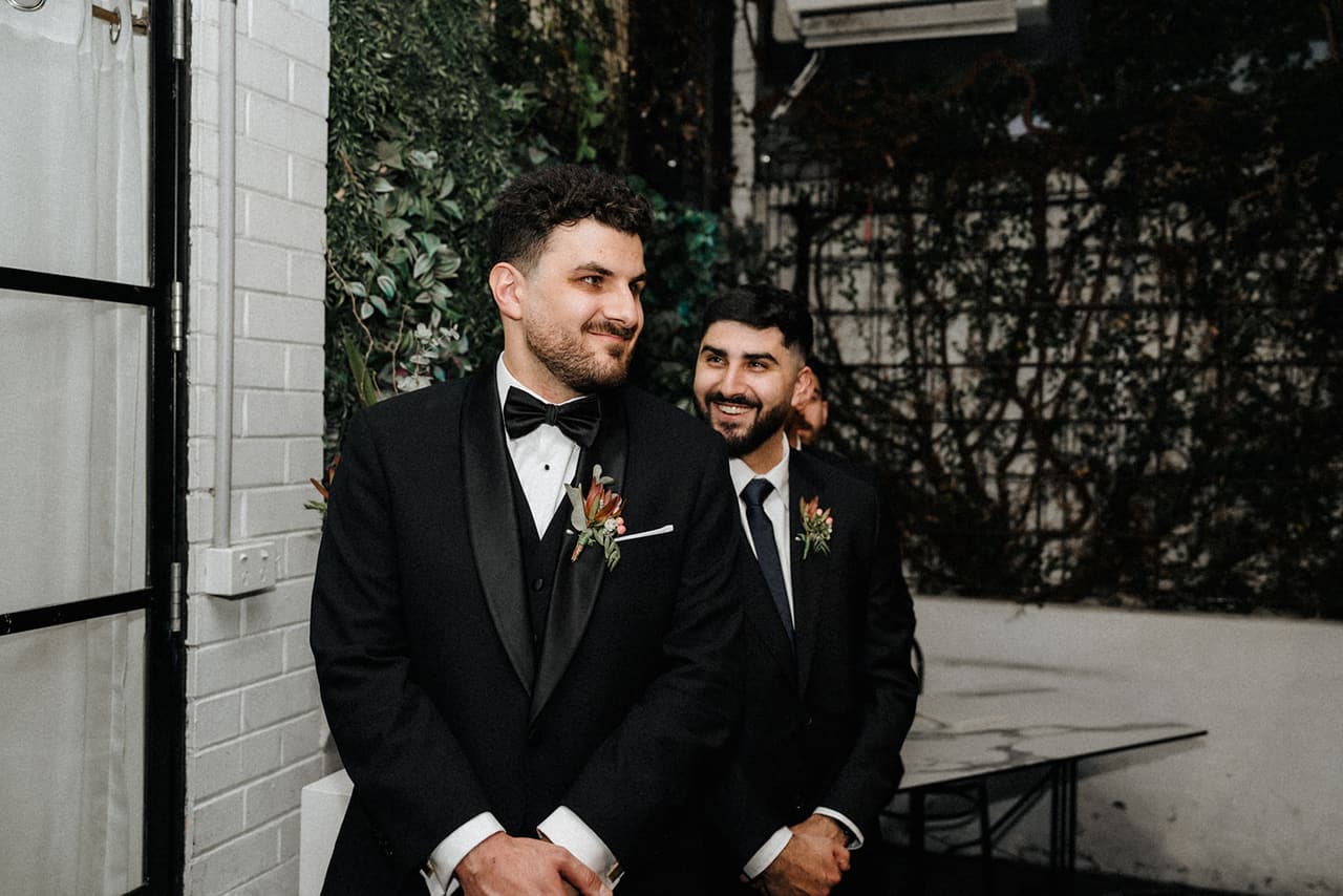 George and a groomsman grinning as they wait at the front of the courtyard