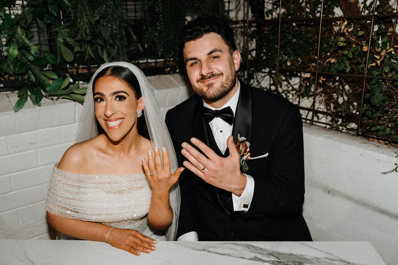 George and Tia grinning as they show their rings after signing