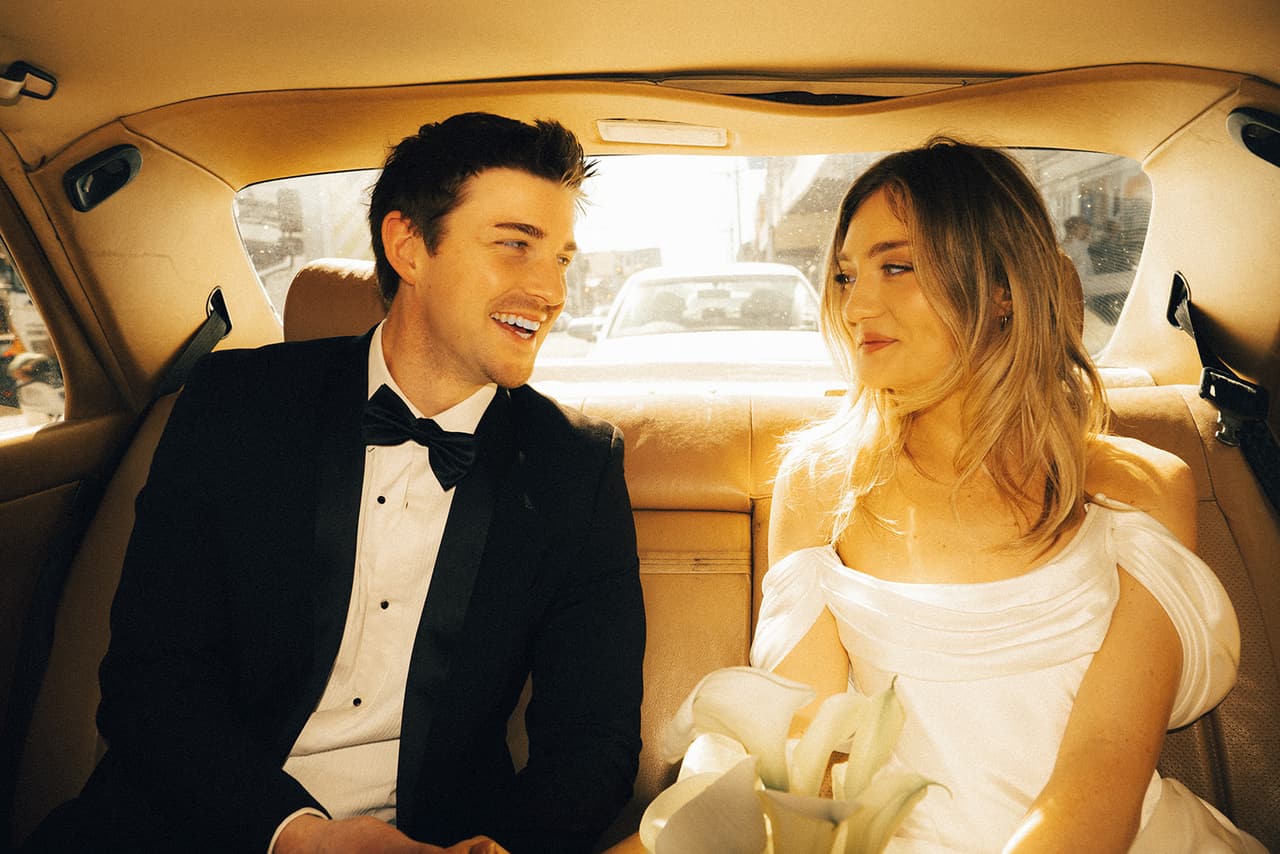 Josh laughing and Hannah smiling at each other in the back seat of the Mercedes