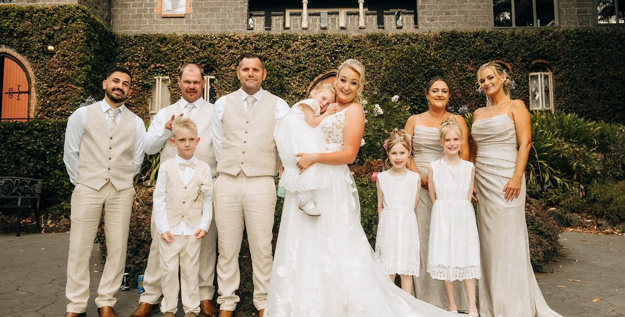 Jenna and Nick with the bridal party and the children in front of the ivy-covered castle