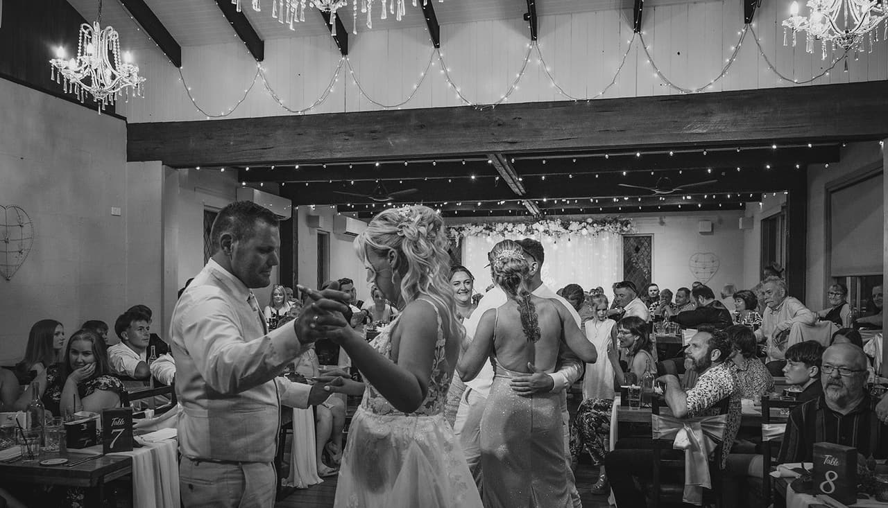 Black and white photo of guests filling the dance floor around Jenna and Nick