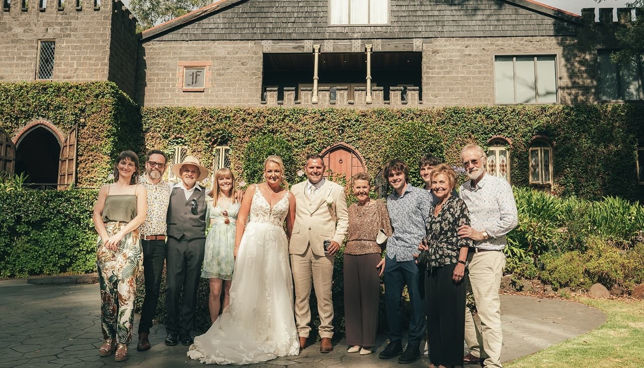 Jenna and Nick with a large group of family on the driveway in front of the castle