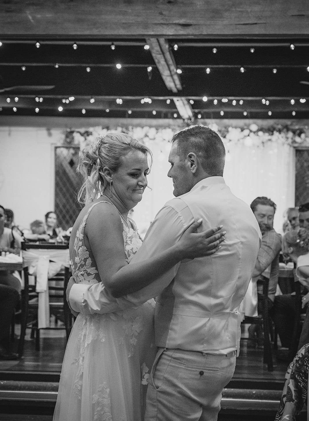 Black and white photo of Jenna and Nick dancing close during their first dance