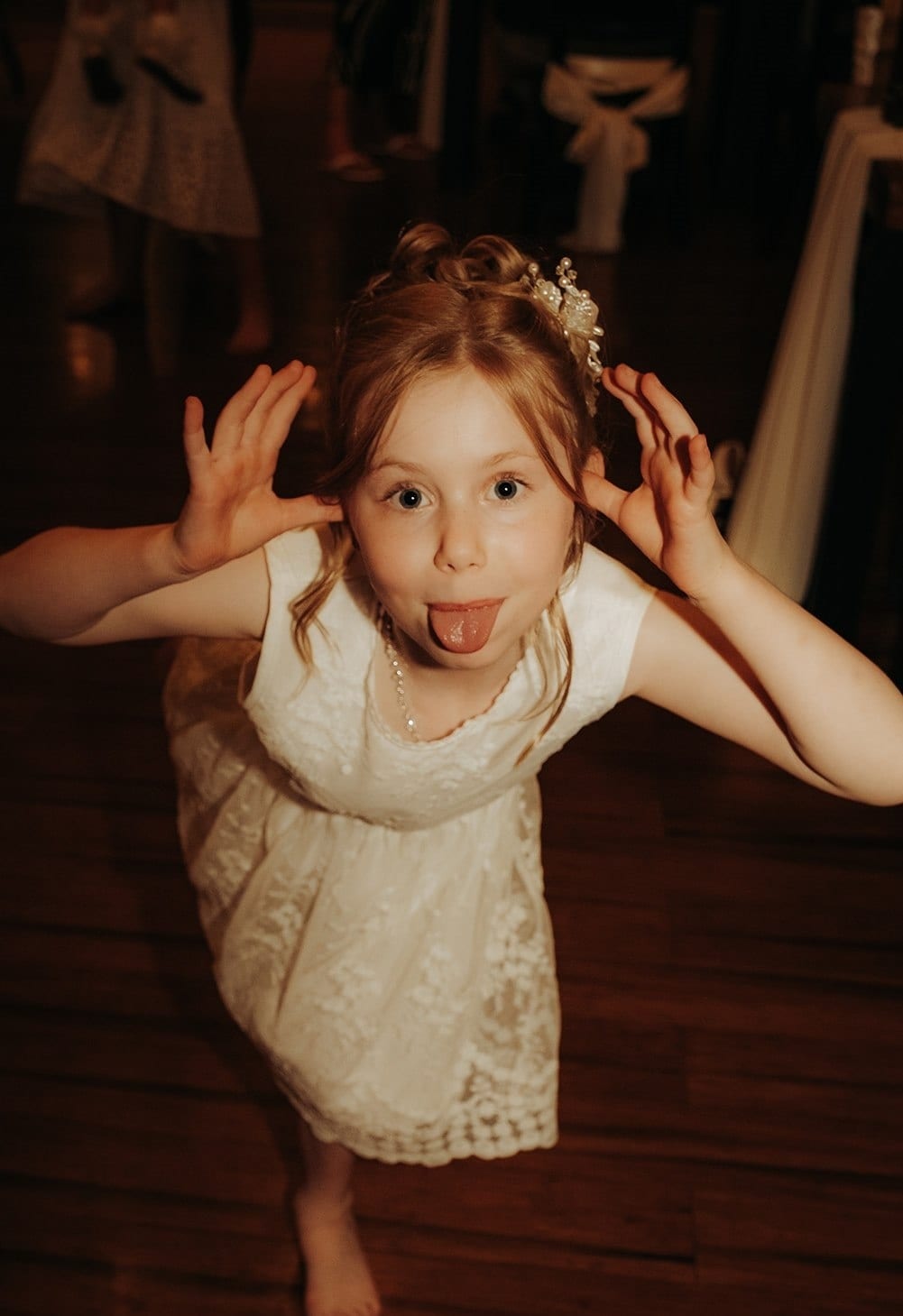 A flower girl pulling a face on the timber dance floor