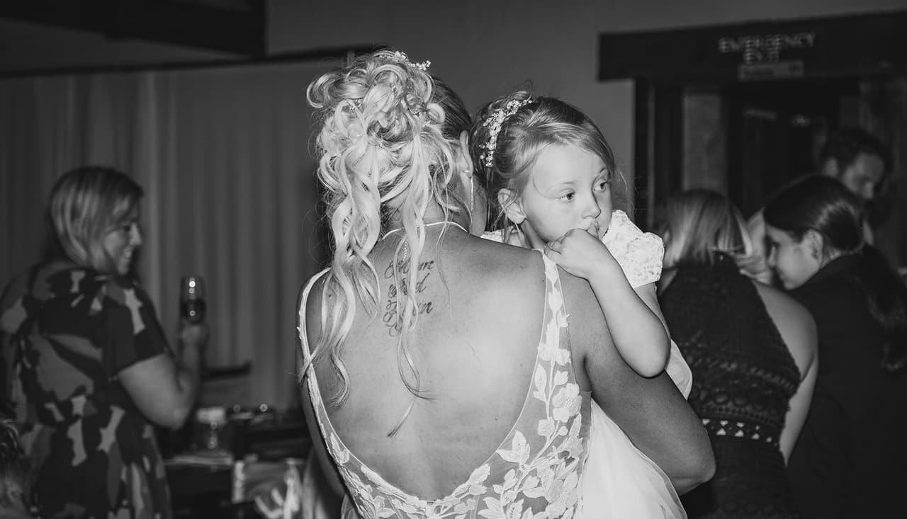 Black and white photo of Jenna from behind holding a child on the dance floor