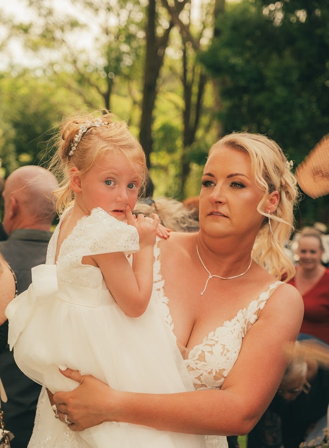 Jenna hugging a little girl in a white dress on the lawn after the ceremony