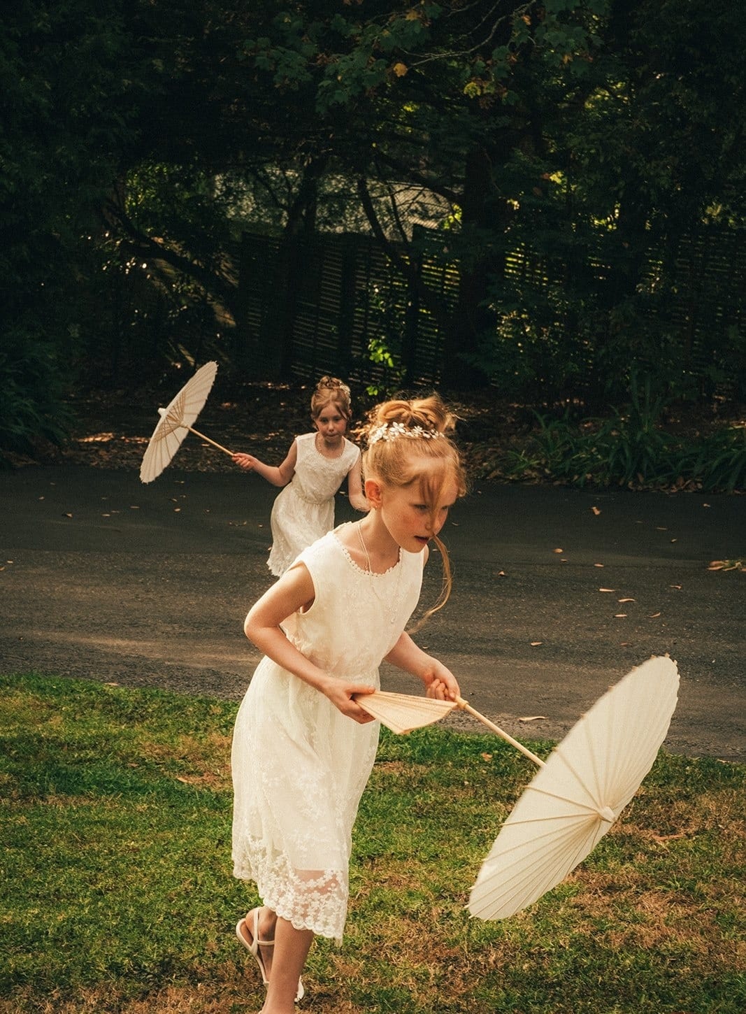 A flower girl twirling a white parasol on the lawn