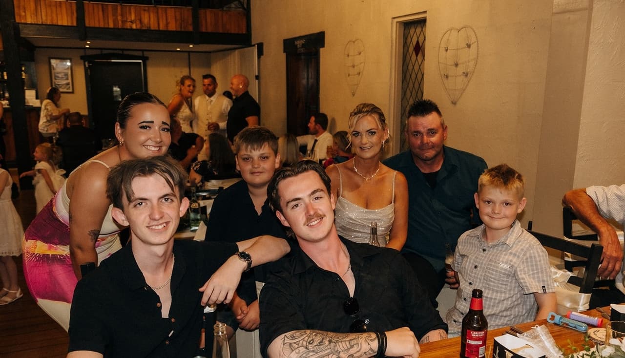 A table of young guests smiling at the camera during the reception