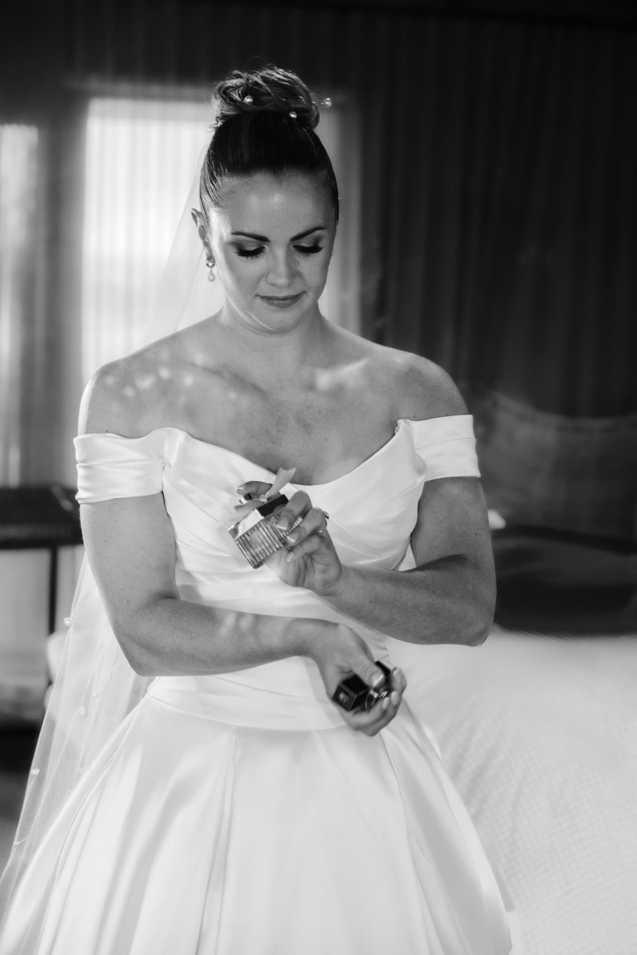 Black and white photo of Jessica putting on perfume before the ceremony