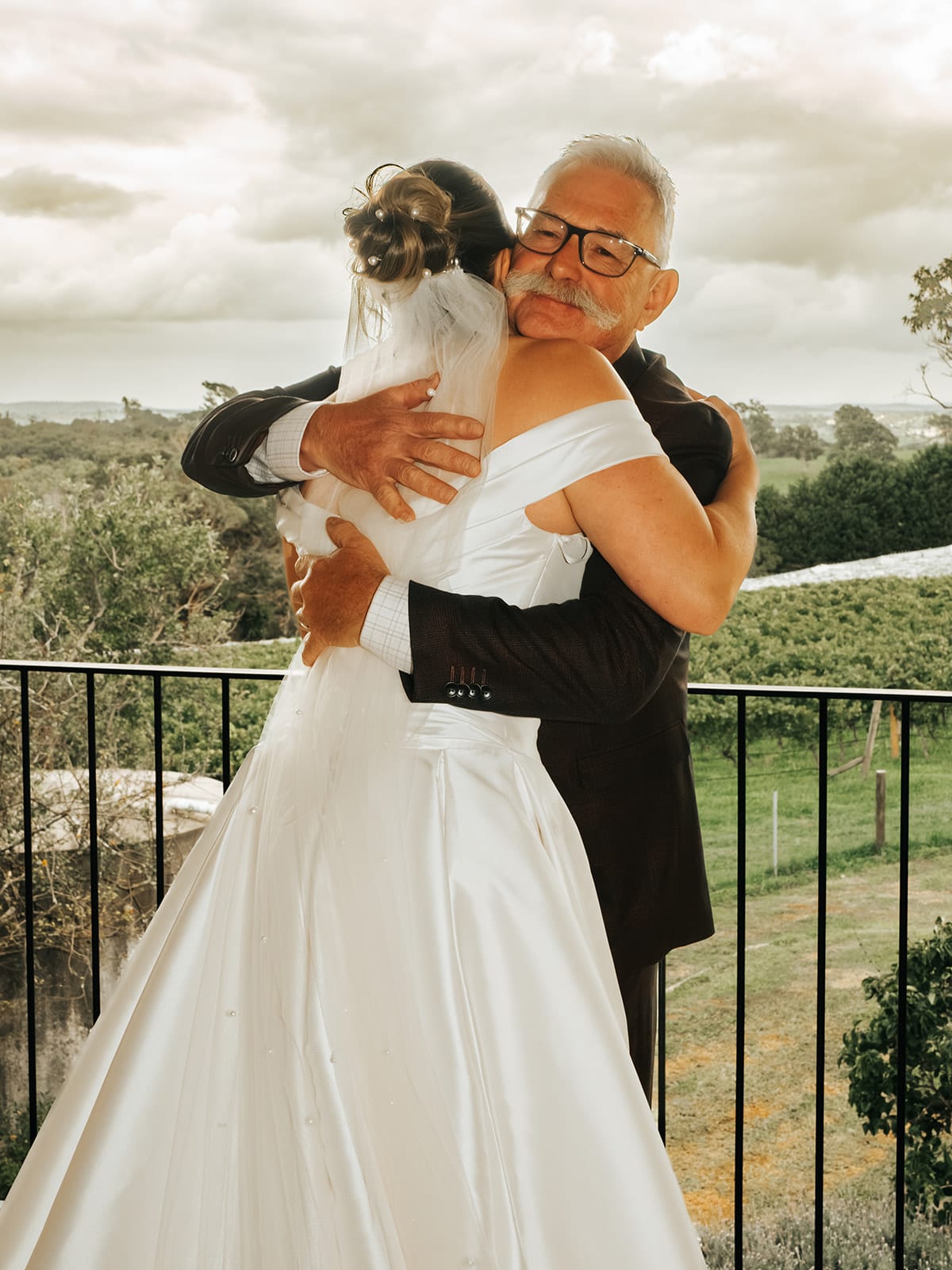 Jessica’s dad hugging her on the balcony, the vines and hills behind them