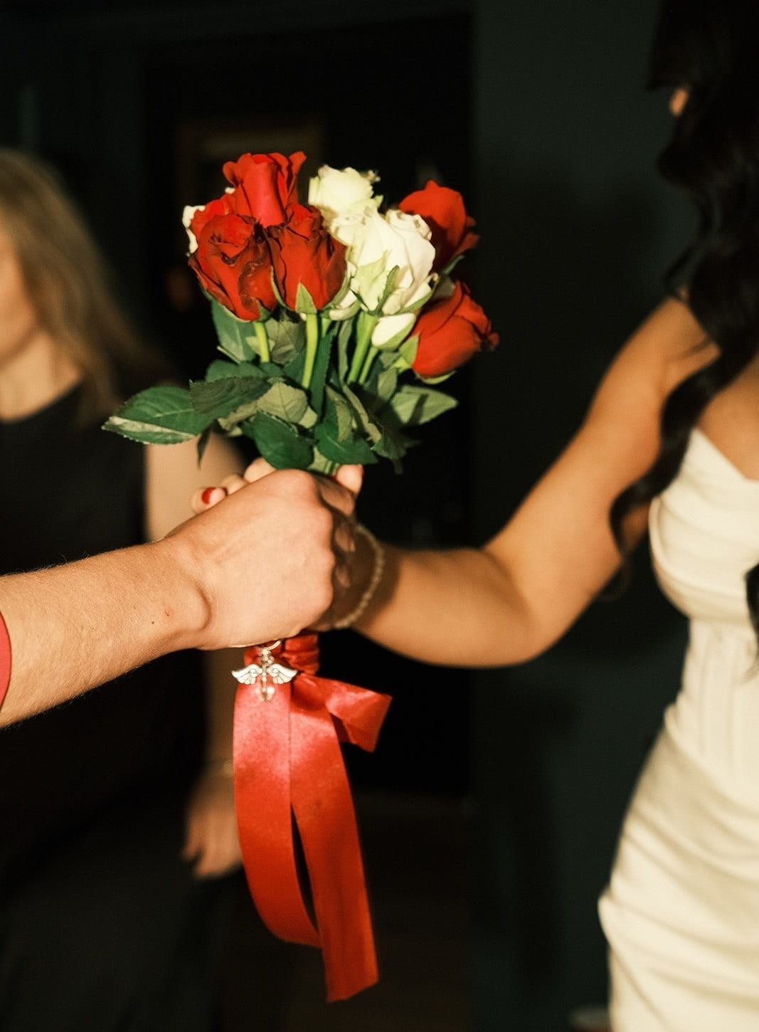 Joanna’s bouquet of red and white roses tied with a long red ribbon