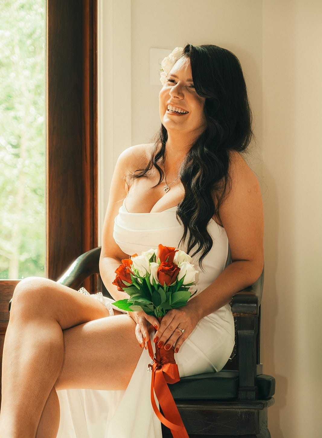 Joanna sitting by the window with her bouquet on her knee, laughing