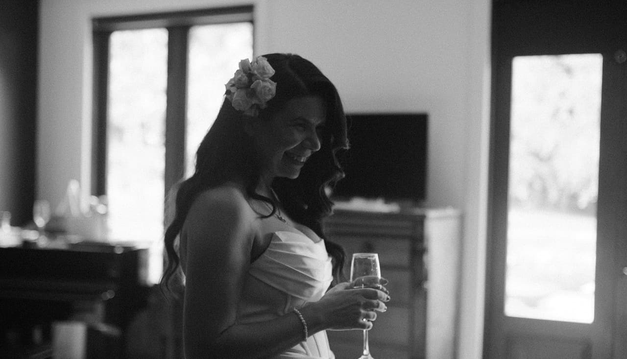 Black and white photo of Joanna in her gown, smiling with a glass of champagne