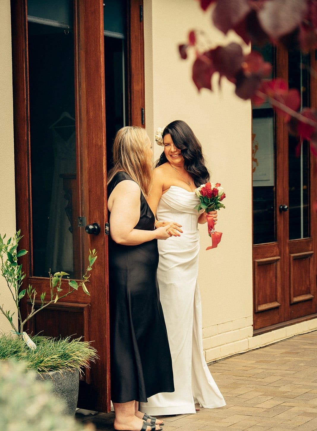 Joanna hugging a woman in a black dress at the door before the ceremony