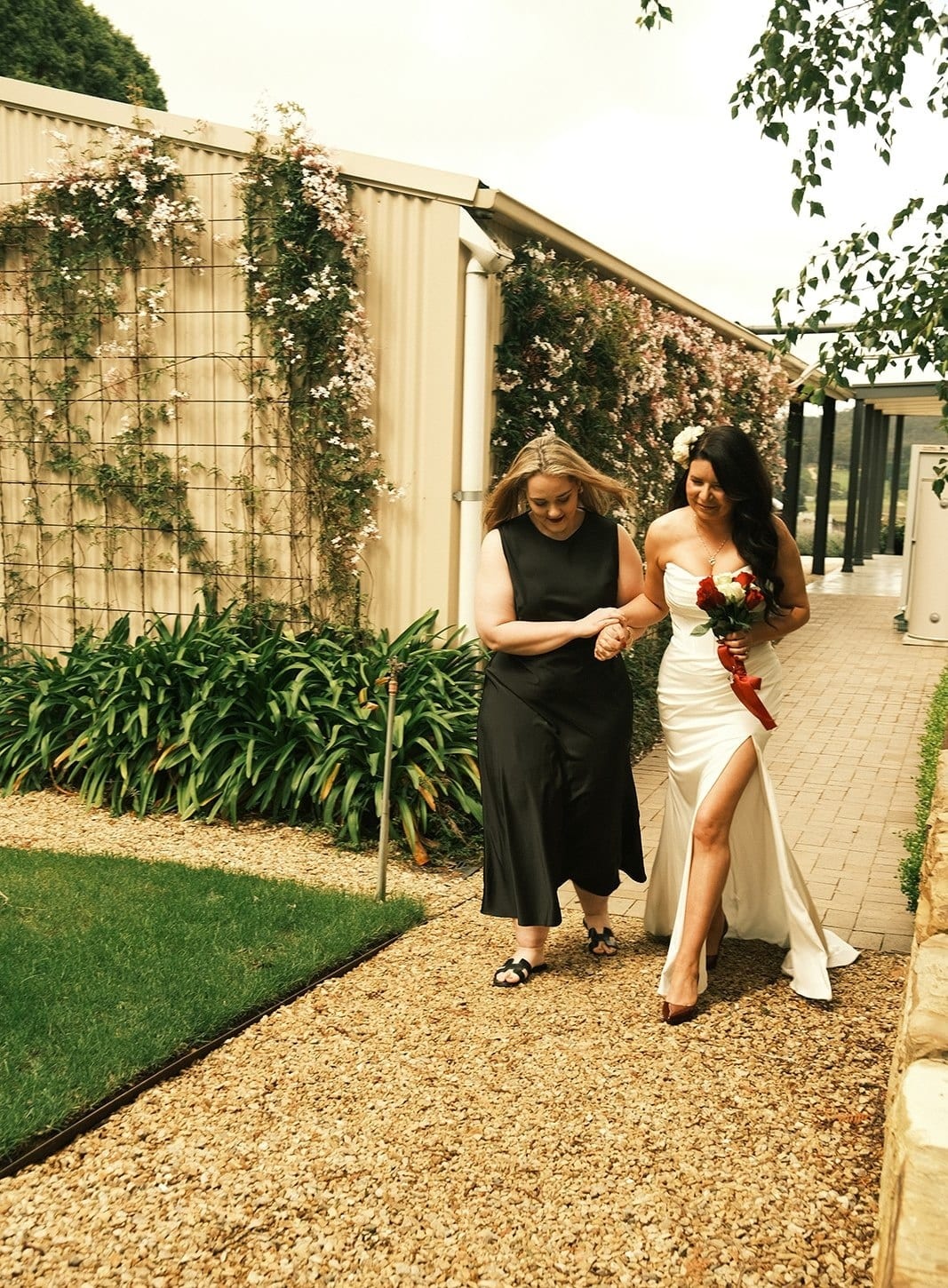 Joanna walking along the gravel path beside the house towards the garden