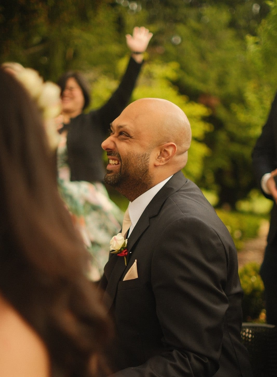 A guest cheering with a raised arm behind Krish after the ceremony
