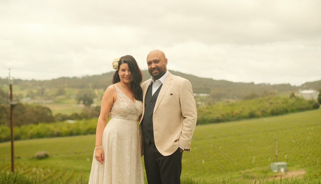 Joanna and Krish standing side by side above the green hills of Summertown