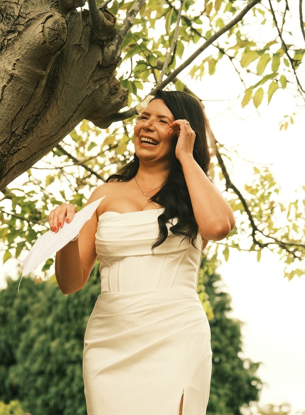 Joanna laughing as she reads her vows under the tree