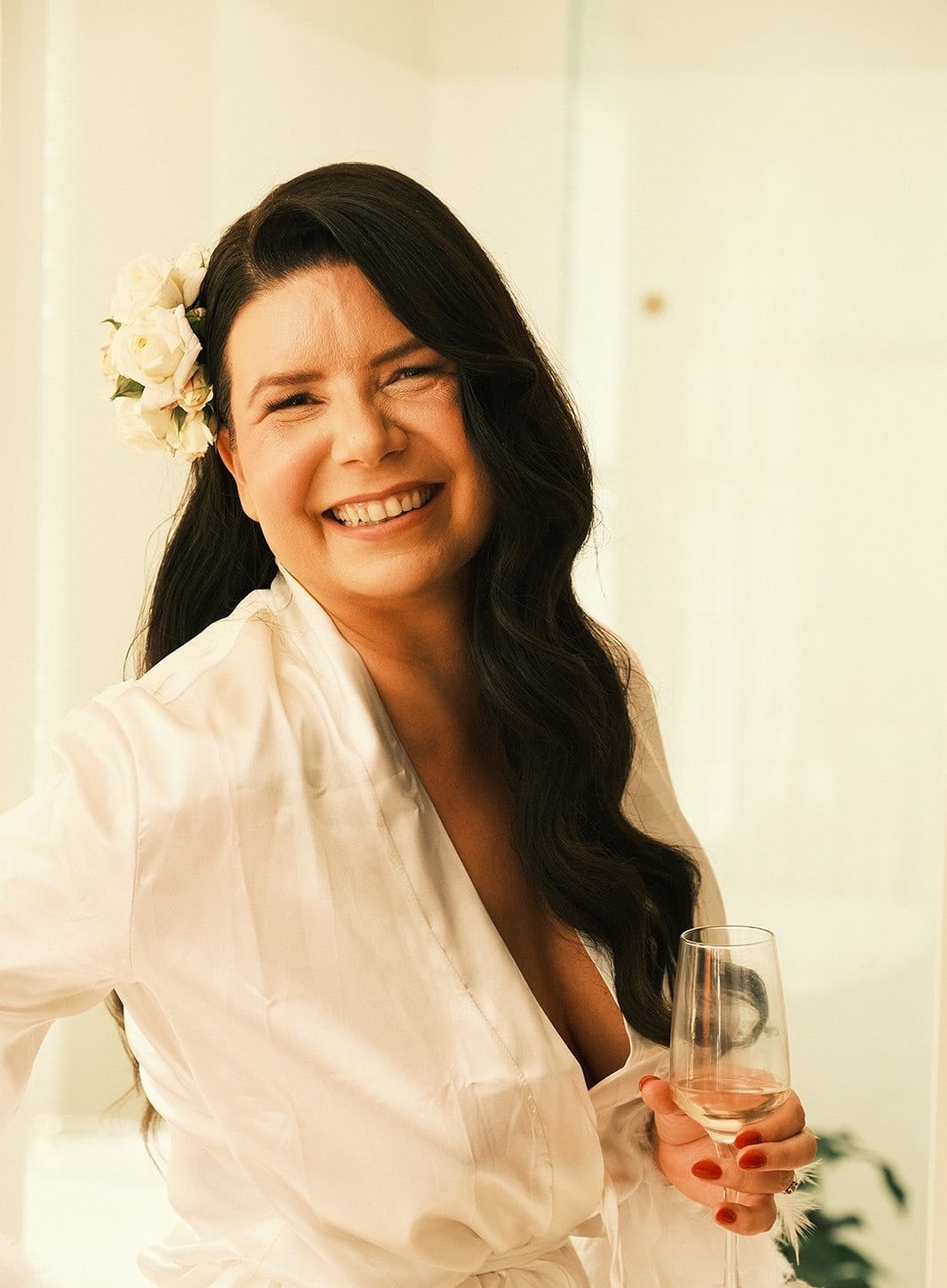 Joanna in a white robe with roses in her hair, laughing