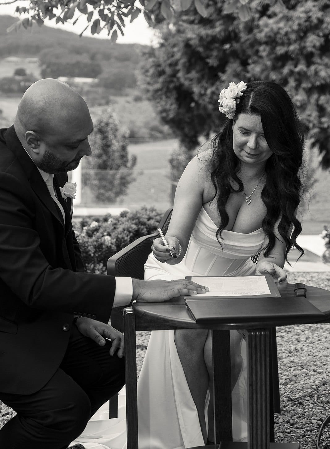 Black and white photo of Joanna signing at a small round table with Krish beside her