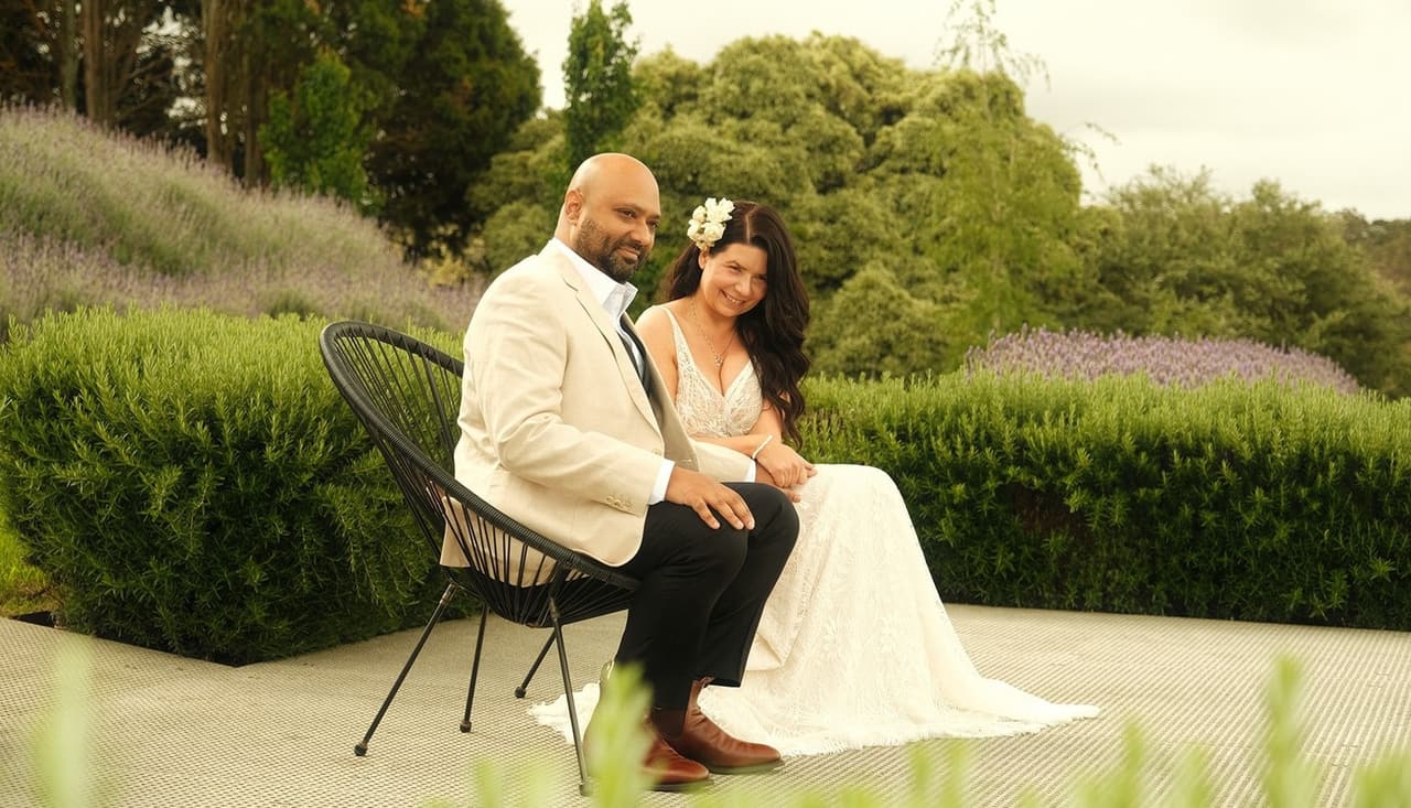 Joanna and Krish on two black chairs on a terrace looking out over the hills
