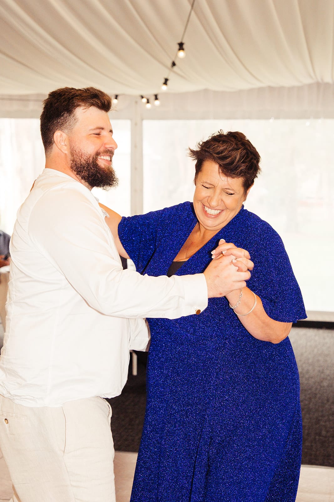 Bronson laughing as he dances with a woman in royal blue