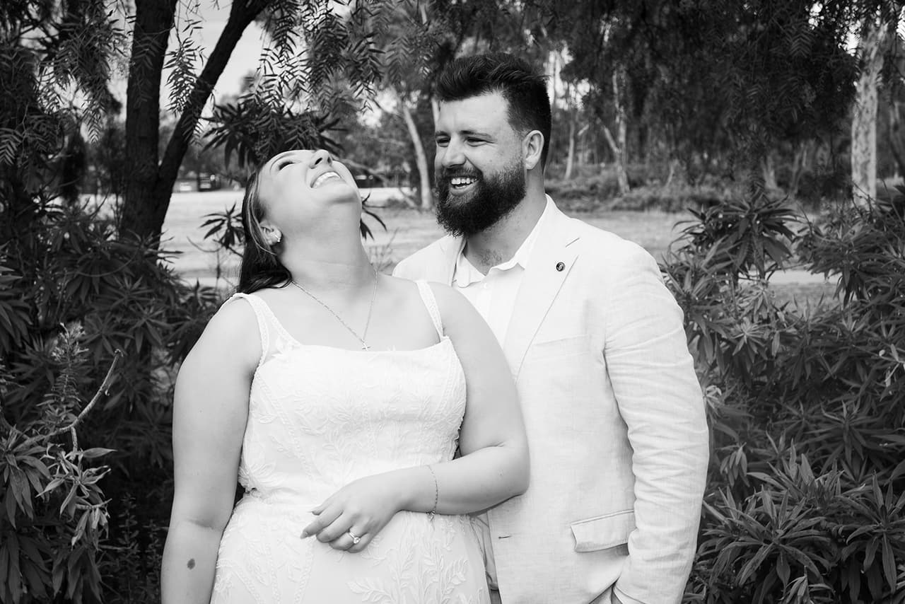 Black and white photo of Karina laughing with her head thrown back as Bronson grins
