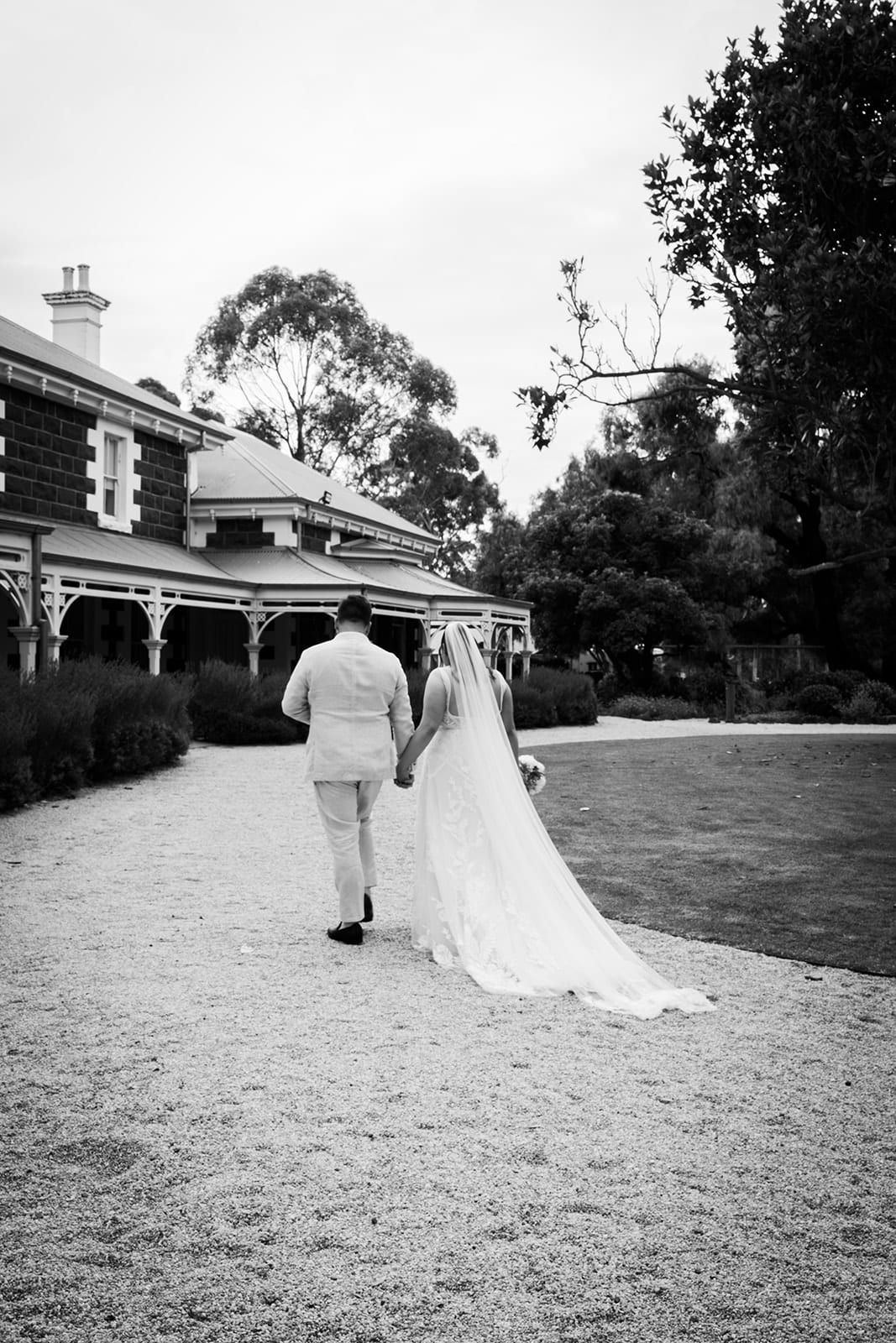 Black and white photo of Karina and Bronson walking back along the drive towards the homestead