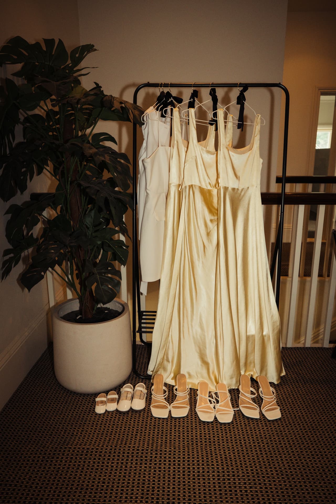 The bridesmaids' champagne dresses hanging on a rail, their shoes lined up underneath