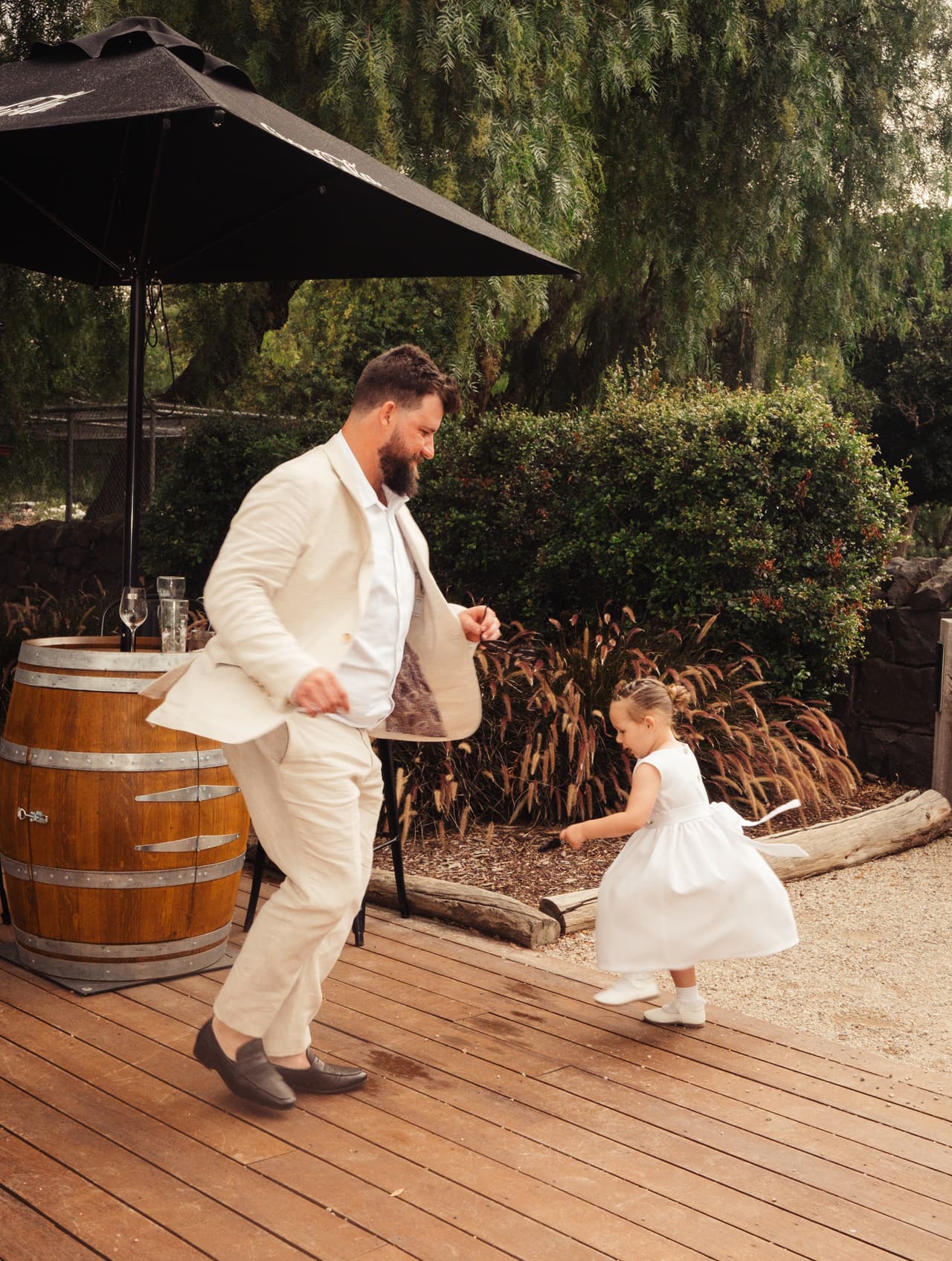 Bronson dancing with the flower girl on a timber deck beside a wine barrel