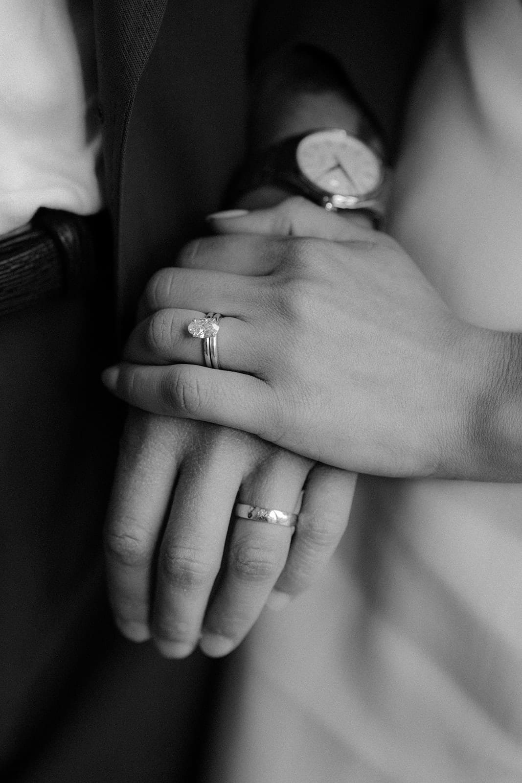 Black and white close up of Karina and Chris holding hands, their rings showing