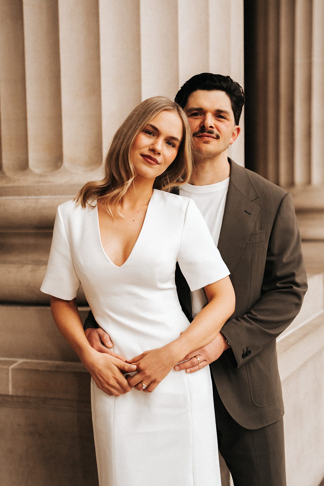 Karina smiling in Chris’s arms as they lean against a sandstone column