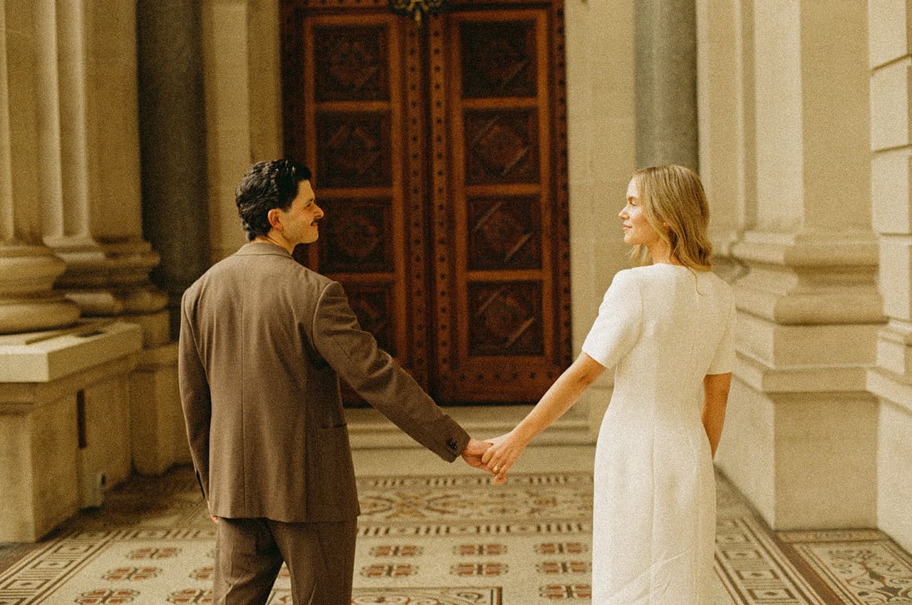 Karina and Chris walking hand in hand towards the carved timber doors of Parliament House, on 35mm film