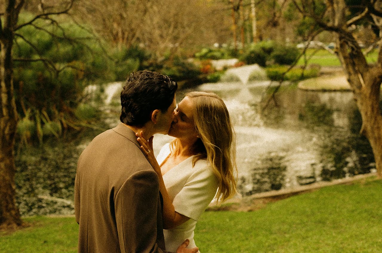 Karina and Chris kissing beside the fountain in Treasury Gardens, on 35mm film
