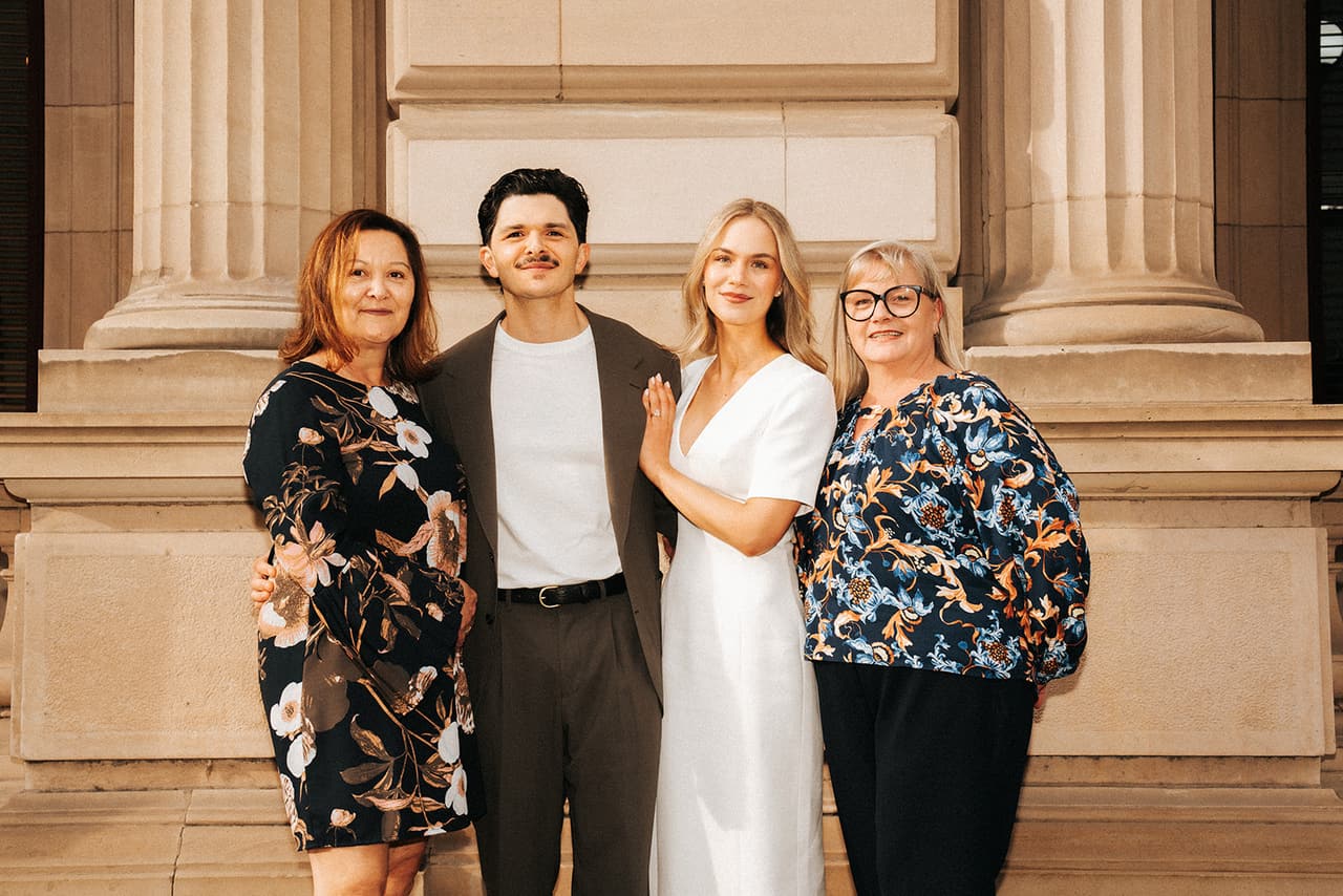 Karina and Chris with their mums in front of the sandstone columns