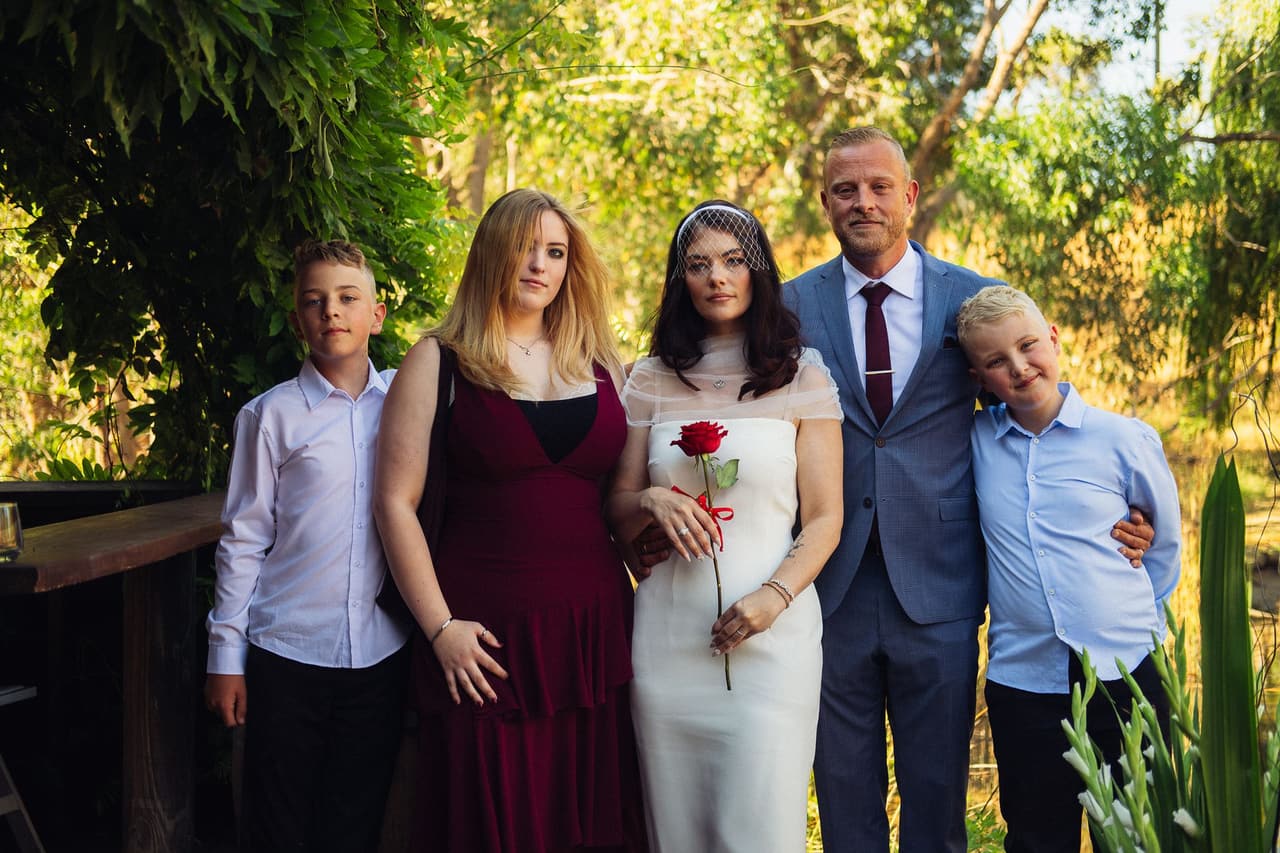 Kim and Ben on the deck with a young woman in a burgundy dress and two boys