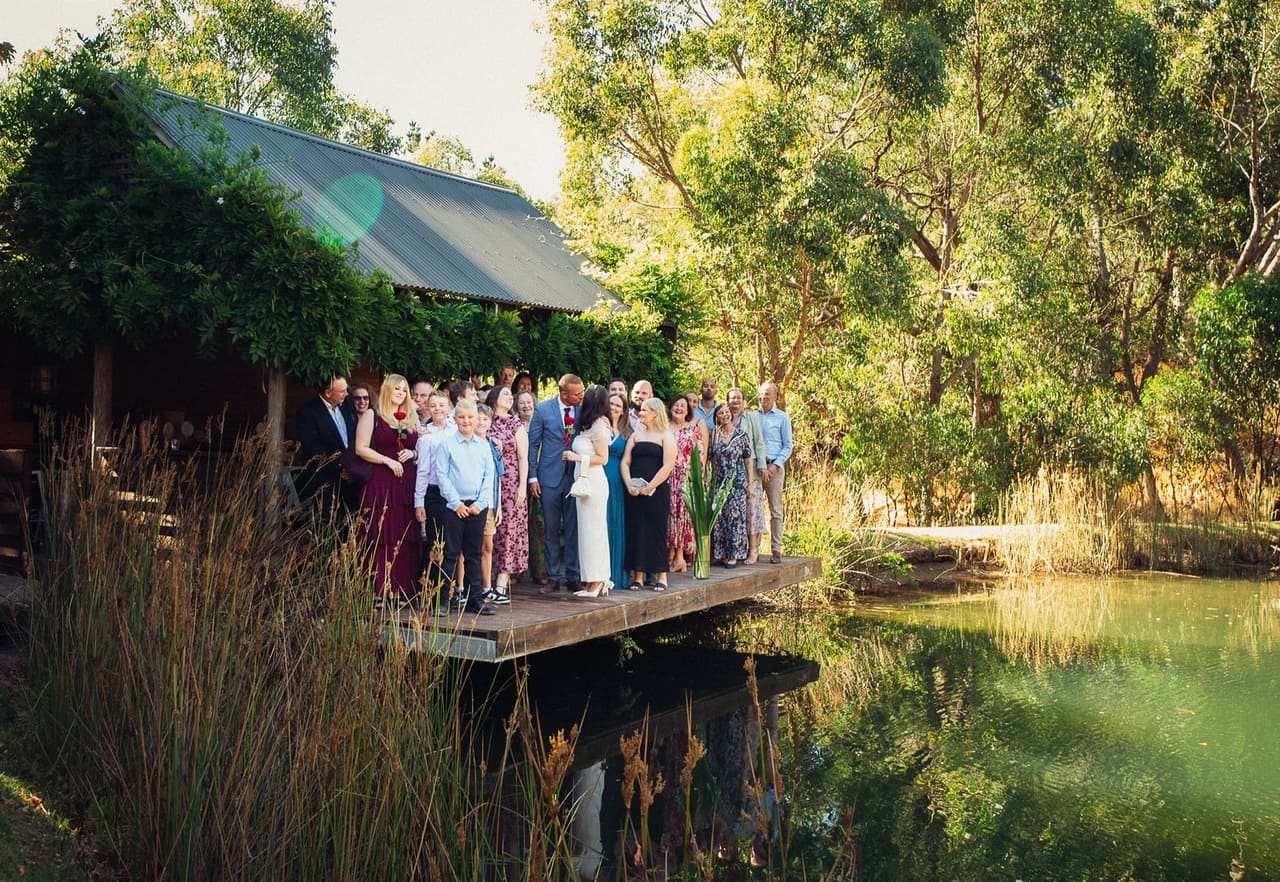 Kim, Ben and their guests gathered on the Boatshed deck over the water, seen from across the pond